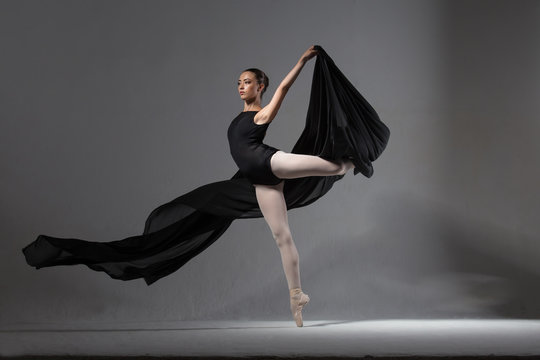 Fototapeta Graceful ballerina in black tights posing with black cloth