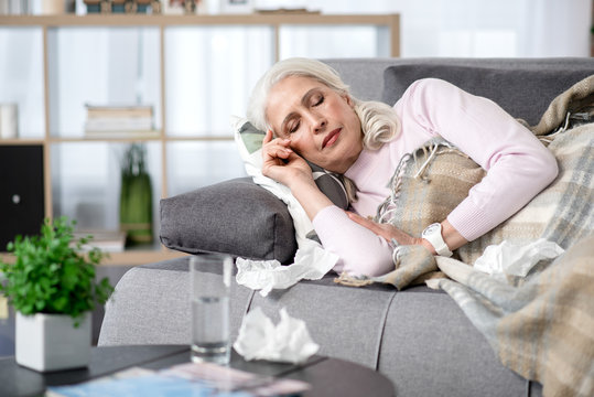 Sick senior woman lying on sofa at home