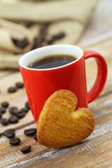 Biscuit in shape of heart leaning against coffee mug
