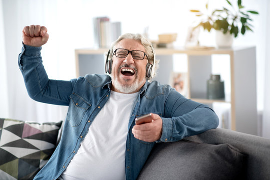 Cheerful Mature Man Listening To Music From Smartphone