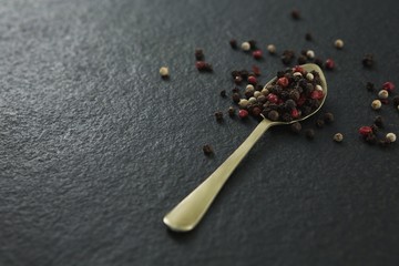 Black pepper and white pepper seeds in a spoon