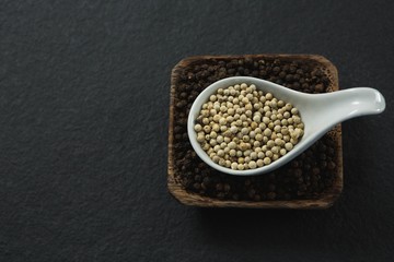 Black pepper and white pepper seeds in a bowl