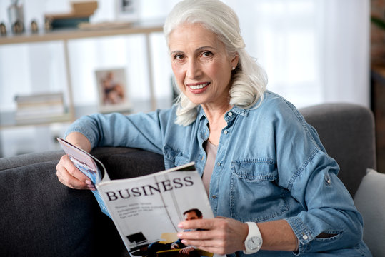 Cheerful mature woman is interested in business news