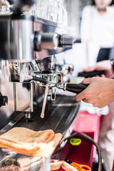 Barista making coffee grinding freshly roasted coffee beans in cafe