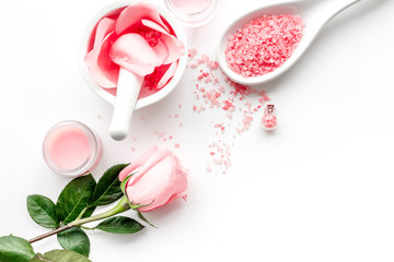 Make cosmetics with rose  oil. Mortar with rose petals and pestle on white background top view copyspace