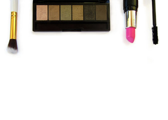 Makeup essentials (lipstick, eyeshadow, brush, mascara) flatlay on a white background.