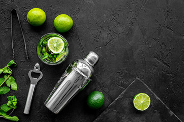 In the bar. Shake mojito. Lime, mint., barman tools on black background top view copyspace