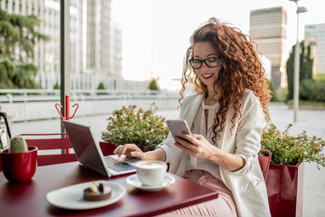 Young business redhead woman on the computer and mobile phone.