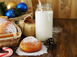 Donut berliner and a glass of milk surrounded by Christmas attributes on a wooden background