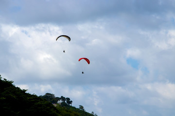 Flying two paragliders over the mountain with views of the horizon.