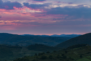 Beautiful sunrise with some fog between the hills with vineyards in Tuscany in Italy