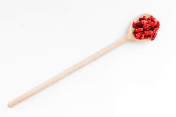 Wooden spoons with dried goji berries on white background top view copyspace