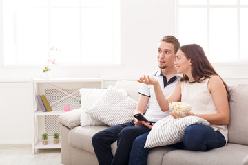 Smiling young couple watching TV at home