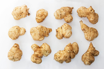 The tubers of Jerusalem artichoke are set in rows on white background