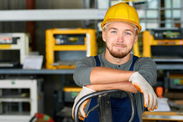 Portrait of cheerful young worker wearing hardhat posing looking at camera and smiling enjoying...