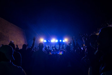 Fans raising hands at a music festival and blue concert lights