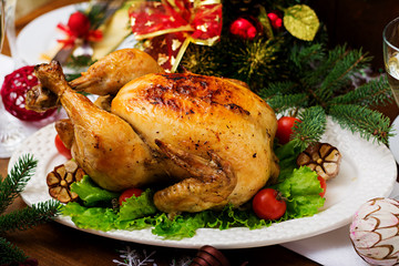 Baked turkey or chicken. The Christmas table is served with a turkey, decorated with bright tinsel and candles. Fried chicken, table. Christmas dinner.