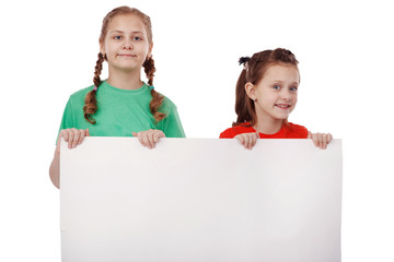 two happy little girls with a blank sheet of paper isolated on white