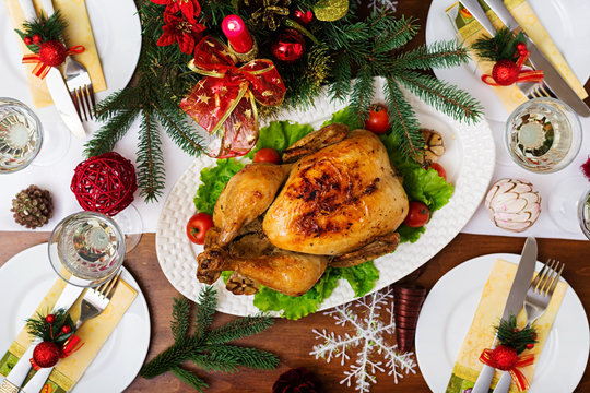 Baked turkey or chicken. The Christmas table is served with a turkey, decorated with bright tinsel and candles. Fried chicken, table. Christmas dinner. Flat lay. Top view
