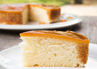 Sliced caramel custard cake on white plate. Sweet and moist dessert. Layer of vanilla cake with  caramel custard.
