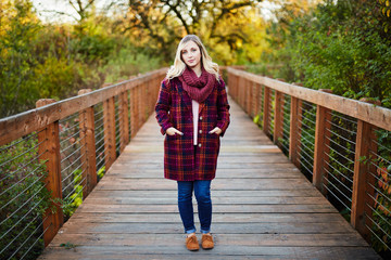 young blond woman on bridge during autumn at camera