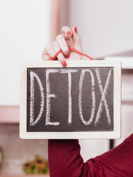 Happy woman holding board with detox sign