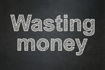 Obraz premium Money concept: text Wasting Money on Black chalkboard background