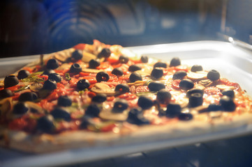Pizza on a metal baking tray in home electric oven