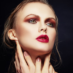 Close-up beauty face of young woman with bright professional make-up and clean skin over dark background