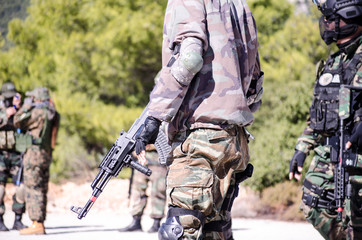 Airsoft game team soldiers keep rifle forest background