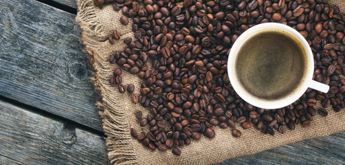 Fried coffee beans. Coffee mug on the background of coffee beans. Panorama, banner.