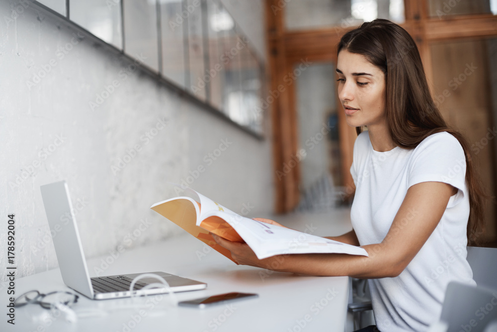Aufkleber young beautiful student reading a workbook and using a laptop computer in university or school campu