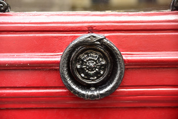 Poignée de porte en fer forgé noir sur bois rouge