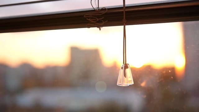 Blinds on a window against a city skyline background at sunset with blur. slowmotion. HD. 1920x1080