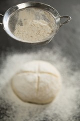Close up of strainer over bun dough
