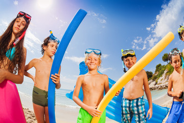 Group of kids on the beach with swimming sticks
