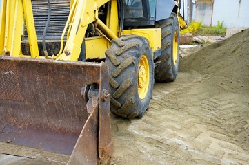 The concept of agronomy, a yellow tractor with a bucket demonstrates work