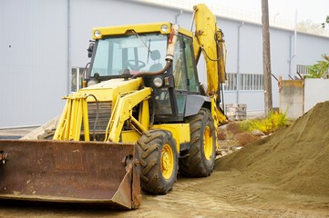 The concept of agronomy, a yellow tractor with a bucket demonstrates work
