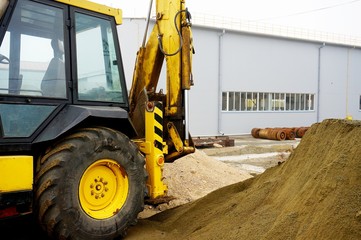 The concept of agronomy, a yellow tractor with a bucket demonstrates work