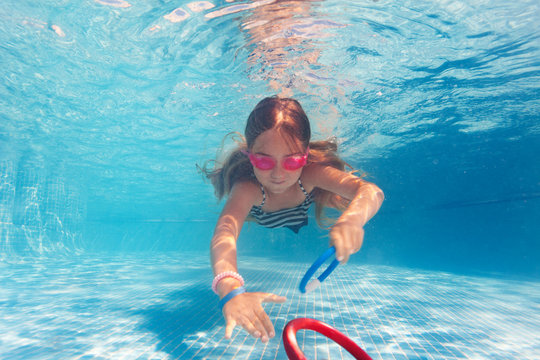 Preteen girl in pink goggles training under water