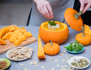 Woman cooking Halloween soup form pumpkin