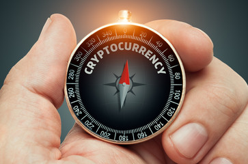 hand holding compass and needle pointing cryptocurrency word