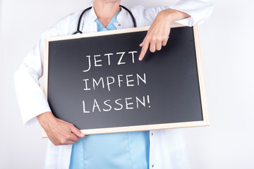Doktor mit Schild jetzt impfen lassen