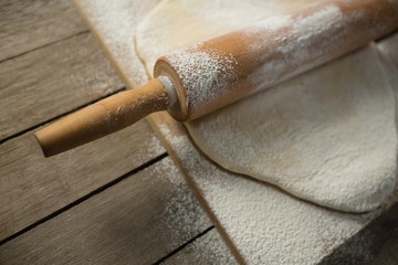 High angle view of rolling pin on rolled dough over cutting
