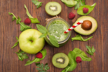 healthy green smoothie with banana, spinach, avocado and kiwi in a glass bottles on a rustic