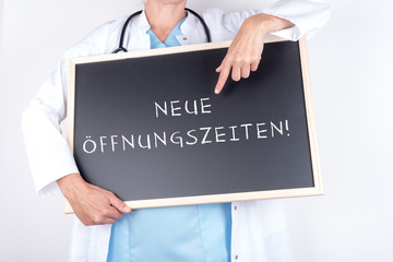 Arzt mit Schild Öffnungszeiten für Praxis