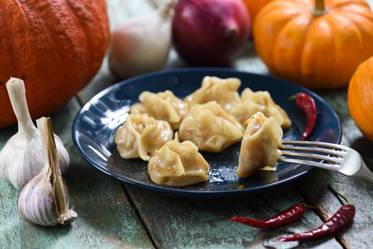 Vegan pumpkin manti, traditional homemade steamed dumplings served with pumpkins, garlic and onions on shabby rustic table