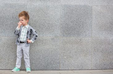 Obraz na płótnie Canvas Fashion kid with glasses near gray wall