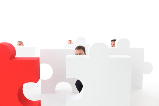 Business people hiding behind puzzle
