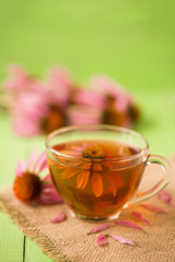 Cup of echinacea tea on green wooden table